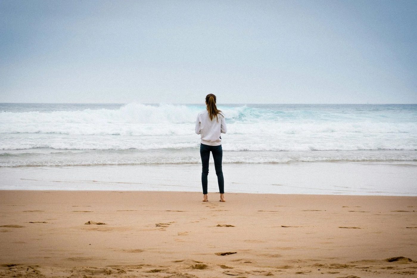 A woman standing alone at the water's edge