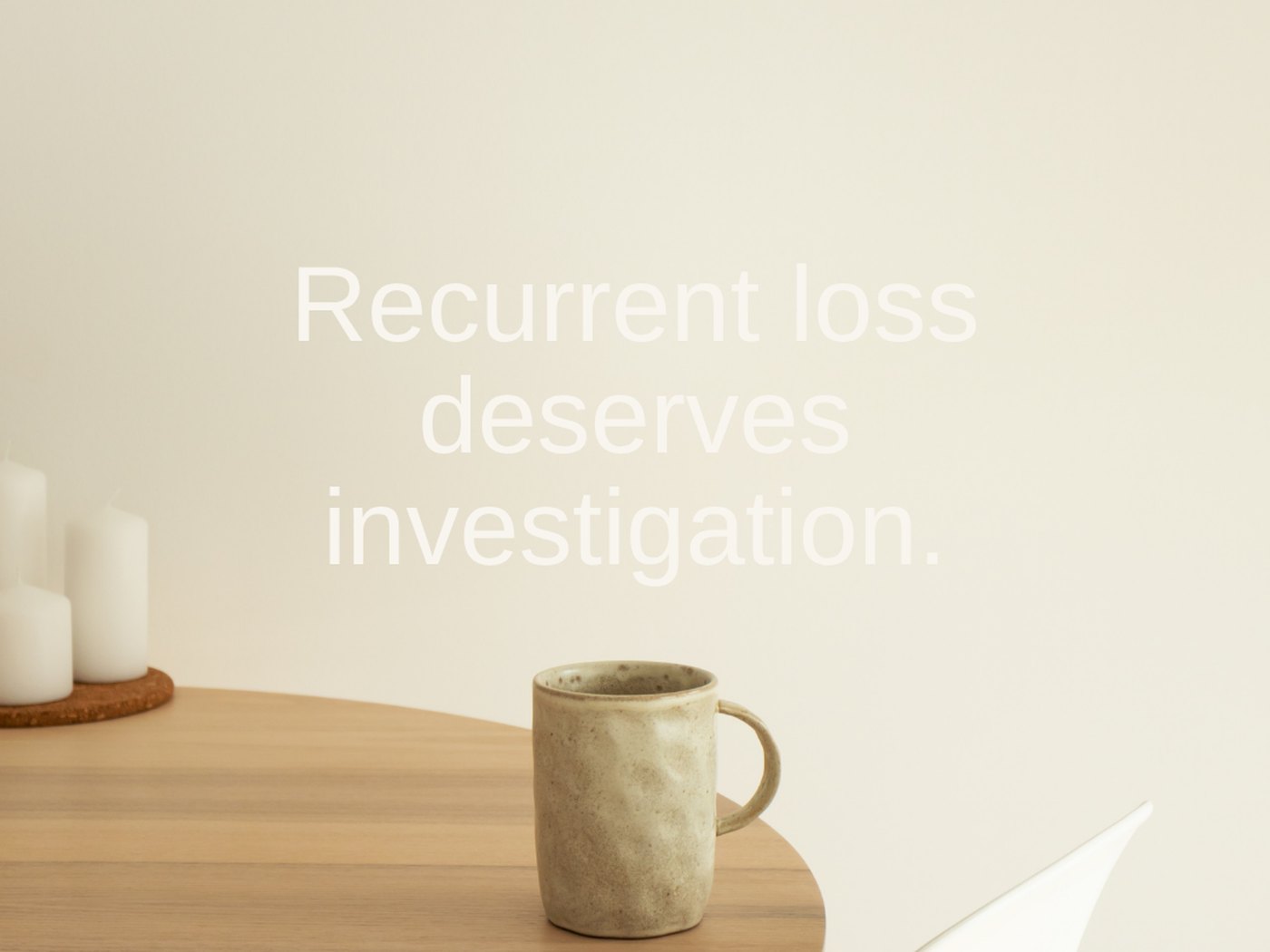 The words &ldquo;Recurrent loss deserves investigation&rdquo; on a soft cream wall above a table with candles and a mug