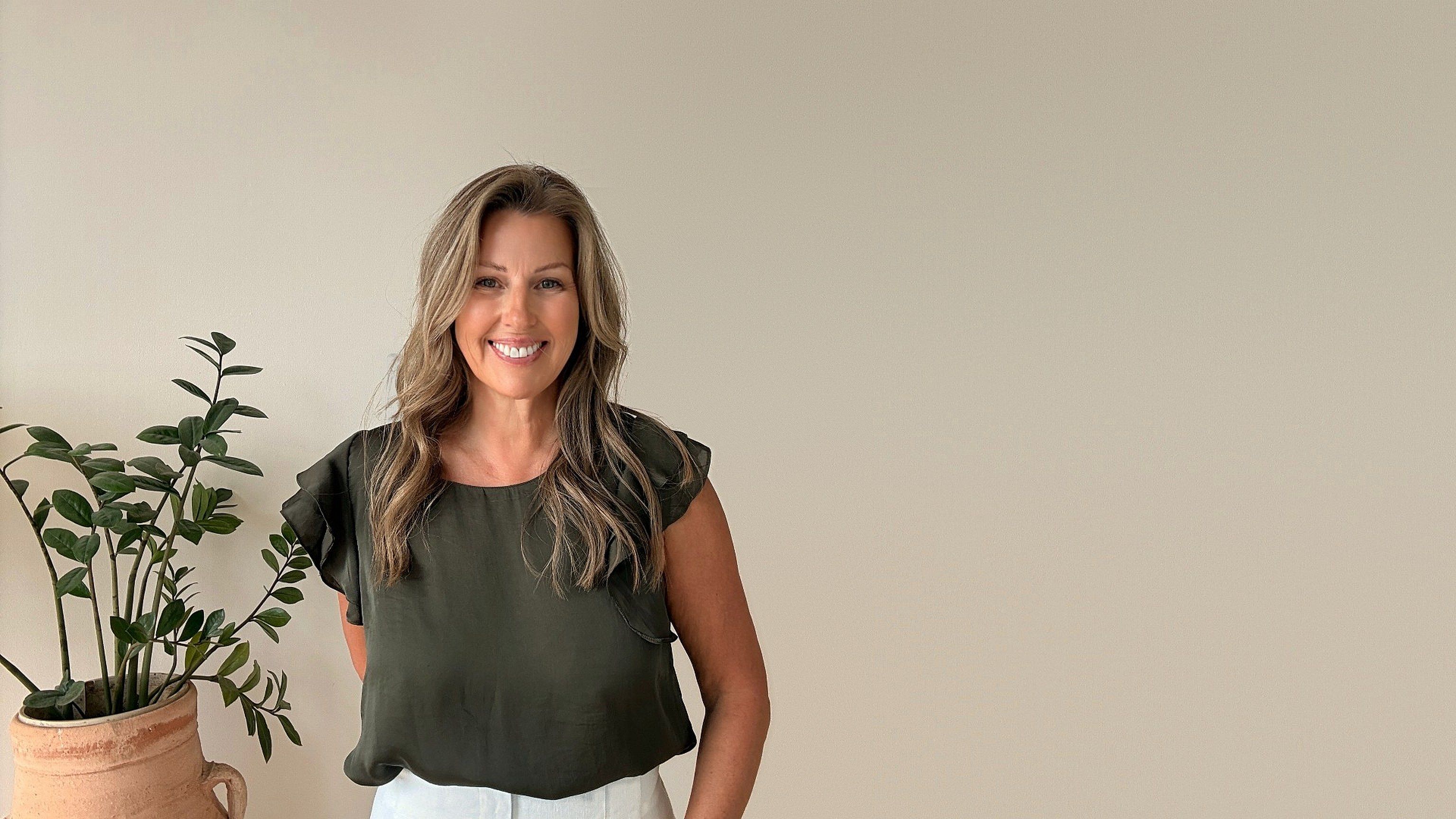 Teena Dunn, founder of Just Keep Trying, in a green top beside a plant