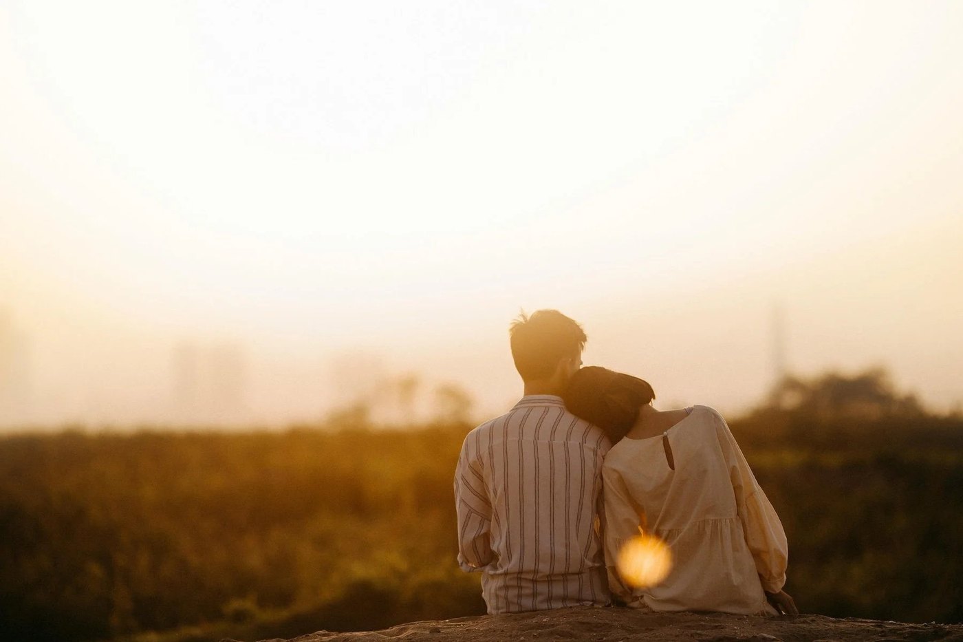 Two people sitting close together at sunset